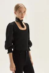 Top de calce ajustado color marrón, con escote cuadrado y mangas largas abullonadas de tela lisa. Los puños de las mangas son elastizados.