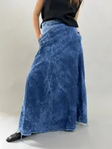 Falda larga de jean denim con efecto de lavado ácido y diseño de paneles geométricos cosidos. Presenta cintura alta, cierre lateral invisible y bolsillos ocultos, con un corte acampanado que aporta volumen y movimiento.