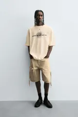 Bermuda de corte relajado en denim de algodón color beige, estilo cargo, con cinco bolsillos y bolsillos plastrón con solapa en las perneras.