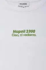 Remera de manga larga color blanco con cuello redondo y diseño de doble capa en las mangas. Presenta un estampado pequeño en el pecho con la frase 'Napoli 1990 Ciao, ci vediamo' en color verde.