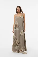 Vestido largo verde militar con estampado floral, silueta amplia y fluida, escote redondeado y breteles con detalle de botones.
