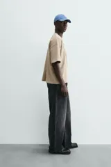 Sudadera de manga corta color beige, corte relajado (relaxed fit) con cuello redondo y número "74" bordado en negro en el frente.