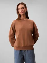 Buzo Calvin Klein de felpa francesa color marrón, con cuello redondo, mangas largas, puños y dobladillo acanalados, y el logo retro de la marca bordado en el pecho.