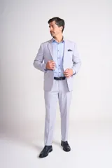 Ambo de dos piezas color gris claro, compuesto por un saco de corte clásico con solapas de muesca y un pantalón de vestir de corte recto con dobladillo en el ruedo.