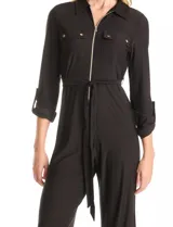 Enterito negro de la marca Sharagano, con escote en V y solapa. Presenta cierre frontal, bolsillos aplicados en la parte delantera, mangas largas con presilla y botón para regular el largo, y lazo de ajuste en la cintura.