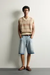 Chaleco relaxed fit de punto tejido en hilatura de algodón, con diseño a cuadros en tonos marrón y beige, cuello en V y acabados en rib en el cuello, las sisas y el ruedo.
