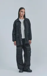 Campera negra de tejido liviano, con cuello camisero, cierre frontal de broches y puños elásticos. Posee múltiples bolsillos frontales con solapa y detalles reflectantes en blanco.