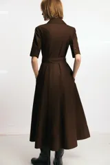 Vestido midi de cuello solapa y escote en pico, con manga corta con vuelta. Presenta bolsillos laterales ocultos, solapas decorativas en el pecho y cierre frontal con botones. Incluye cinturón de lazada en el mismo tejido.