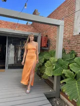 Vestido midi naranja de un hombro con abertura lateral en la falda y detalle de abertura en la cintura.