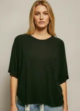 Remera básica oversize de color negro, con mangas cortas tipo raglán y un bolsillo frontal en el pecho. Presenta un corte holgado y un diseño versátil.