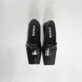 Mocasines negros de charol con punta cuadrada y detalle de antifaz.