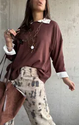 Sweater de punto color chocolate con cuello redondo y mangas largas con puños en contraste color blanco. Presenta un diseño holgado y casual.