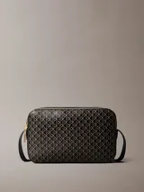 Cartera bandolera Calvin Klein de color negro, con estampado geométrico de monogramas en tono dorado, cierre superior de cremallera y correa ajustable.