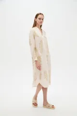 Vestido midi holgado de viscosa color beige, con mangas largas, cuello mao, cierre frontal con botones y detalle de bordado con lurex con diseño de hojas doradas.
