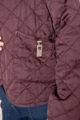 Campera corta de diseño capitoneado con patrón de rombos, color negro. Presenta cuello redondo, cierre frontal abierto, mangas largas y dos bolsillos delanteros con detalle de broche.