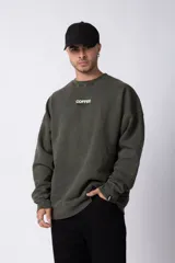 Buzo de cuello redondo en algodón rústico con efecto de lavado gastado, corte oversize y estampa frontal pequeña con texto.