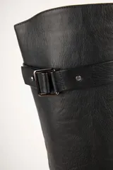 Bota de caña alta color negro, de símil cuero, con aplique de hebilla, cierre lateral y plataforma tipo tractor.