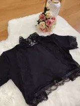 Top de terciopelo negro con cuello alto, detalles de encaje en el cuello y mangas, y paneles de microtul. Presenta espalda descubierta.