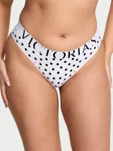 Tanga de tiro bajo confeccionada en microfibra blanca con estampado de lunares negros y cintura elástica con el logotipo de la marca.