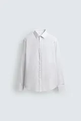 Camisa slim fit blanca de manga larga, confeccionada en tejido de algodón con cuello italiano y puños con botón. Cierre frontal de botonadura.