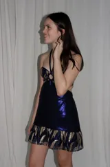 Vestido corto azul metalizado con diseño cut-out, argolla central en el busto, tirantes halter y falda con volado en el ruedo.