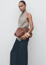 Pantalón de tiro alto con diseño wide leg, confeccionado en tejido de algodón y lyocell estilo denim. Presenta costuras verticales decorativas, bolsillos laterales y cierre oculto con botón, gancho y cremallera.