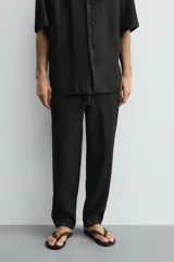 Pantalón relaxed fit de lino color negro, con cintura elástica ajustable con cordón y bolsillos frontales.