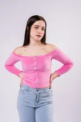 Remera de morley color rosa, con escote off-the-shoulder y cierre frontal metálico plateado. Es de manga larga y corte ajustado al cuerpo.