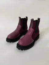 Botas tipo chelsea de cuero, combinando texturas en color bordó. Presentan paneles laterales elásticos en negro, suela track robusta y tiradores en la parte superior.