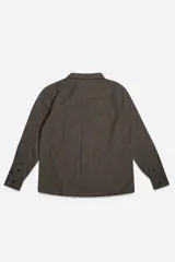 Sobrecamisa de jean color tostado, con cuello clásico, cierre frontal con botones y dos bolsillos frontales con solapa. Presenta mangas largas con puños abotonados y un pequeño parche decorativo en el ruedo.