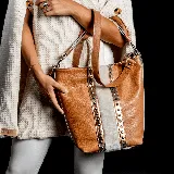 Cartera tote de cuero color marrón claro con laterales de piel sintética blanca y detalles metálicos dorados. Tiene doble asa de mano y correa bandolera desmontable y ajustable.