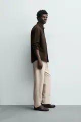 Pantalón de corte relajado confeccionado en una mezcla de algodón y lino. Presenta cintura elástica con cordón ajustable, bolsillos laterales y bolsillos traseros de vivo.