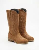 Bota de caña media estilo texano, confeccionada en gamuza color marrón con detalles de costuras bordadas en contraste.