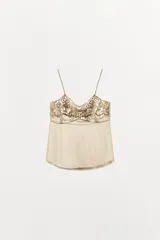 Top de tirantes finos confeccionado en organza semitransparente con estampado floral sutil. Presenta escote en pico con aplicaciones de bordados florales a contraste y terminación en puntilla en el bajo.