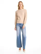 Buzo de tejido lurex en color beige, con cuello redondo y mangas largas con diseño plisado y puños con aplique de botones dorados.