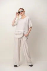 Blusa de lino color blanco, de corte amplio, con escote redondo, mangas cortas y detalle de guarda calada horizontal en la parte inferior.