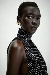 Top halter de viscosa con estampado de lunares, cuello halter, espalda descubierta y detalle de lazadas en el mismo tejido. Cuenta con bajo redondeado y cierre trasero con botones.