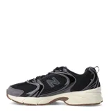 Championes New Balance modelo 530, con diseño retro-deportivo. Presentan una capellada de malla transpirable en color negro con refuerzos sintéticos en tonos grises y negros. Incluyen entresuela con tecnología ABZORB en color crema y suela de goma en tono marrón.