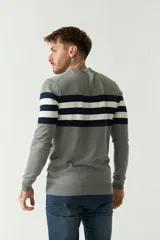 Sweater azul marino con rayas horizontales color crema y rojo, de manga larga y cuello redondo.