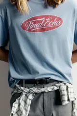 Remera relaxed fit color celeste con efecto lavado, de manga corta y cuello redondo. Presenta un estampado frontal con la inscripción "Final Echo" en el interior de un ovalo rojo.