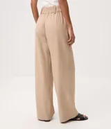 Pantalón wide leg de cintura alta y corte amplio, color beige, con doble botón frontal y bolsillos laterales.
