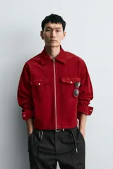 Sobrecamisa de corte boxy fit confeccionada en tejido de pana de algodón con elasticidad. Presenta cuello solapa, cierre frontal con cremallera, mangas largas con puños abotonados y dos bolsillos de plastrón con solapa en el pecho.