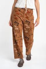 Jean de corte baggy con diseño de tiro medio y estampado floral en tonos tierra sobre base marrón. Confeccionado en algodón peinado de alta resistencia.