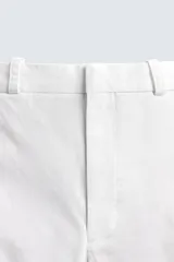 Pantalón chino de corte oversized confeccionado en tejido de algodón con estructura twill. Presenta bolsillos frontales, bolsillos traseros de vivo y cierre frontal con cremallera y gancho metálico oculto.