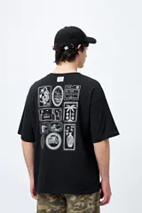 Remera blanca de corte amplio con mangas cortas y estampado de una postal con una palmera y el mar.