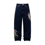 Pantalón de jean color azul oscuro con corte baggy, presenta estampados gráficos estilo tatuaje en ambas piernas.
