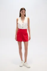 Short de lino color beige, de tiro alto y corte holgado. Presenta bolsillos frontales amplios y detalle de botones decorativos en la cintura.