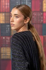 Buzo negro de tejido de punto con rayas verticales plateadas, corte holgado y mangas largas.