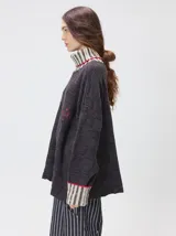 Pullover de punto jacquard con diseño de cuadros en relieve, cuello alto y mangas largas. Presenta detalles de pespuntes en color rojo en el cuello y los puños, aberturas laterales y logo bordado en el pecho.