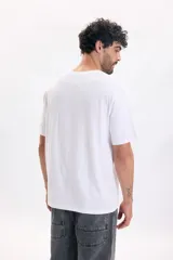 Camiseta blanca de manga corta y corte relaxed, con pequeño estampado tipográfico en el pecho.